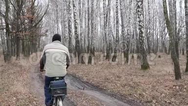 在秋天，一个穿着蓝色连帽衫的人骑着<strong>自行车</strong>沿着一条小路<strong>行驶</strong>，地上有橡子和五颜六色的叶子和树叶，骑着<strong>自行车</strong>沿着一个爸爸